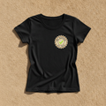 Pre-Revenue fitted tee in black with a small round PRE-REVENUE est. 2026 badge and green check mark, laid flat on a tan background
